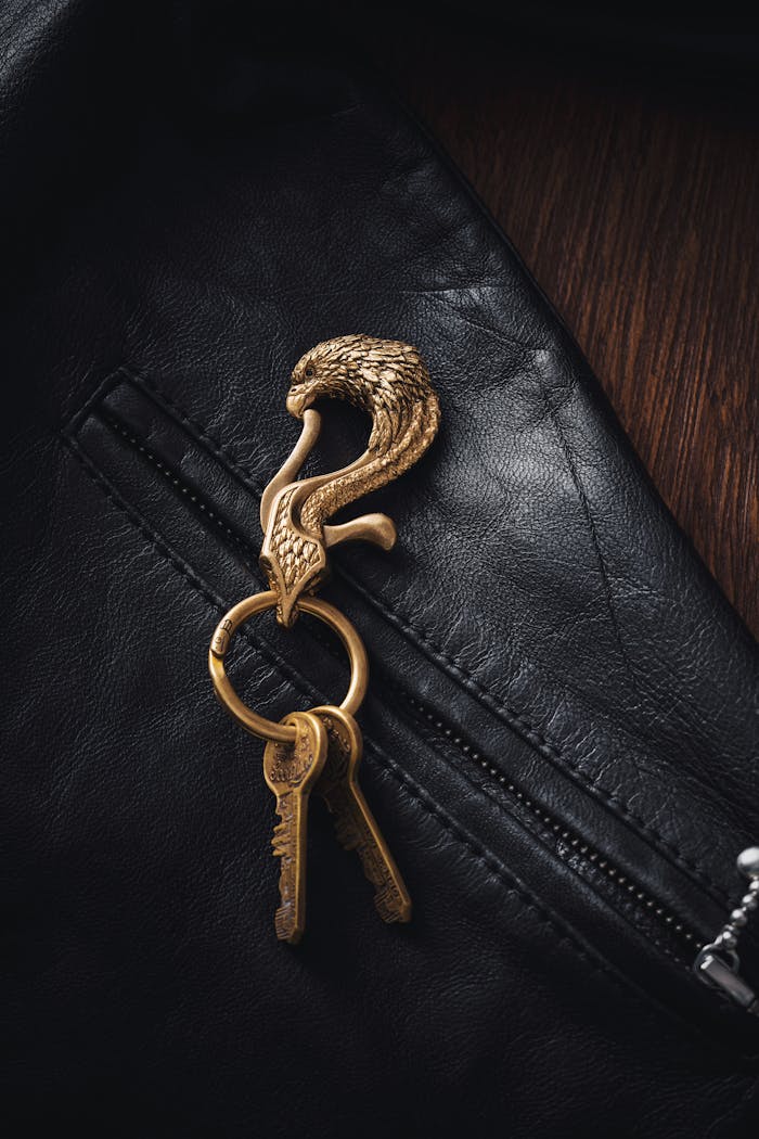 Brass eagle keychain elegantly placed on a black leather jacket with a zipper detail.